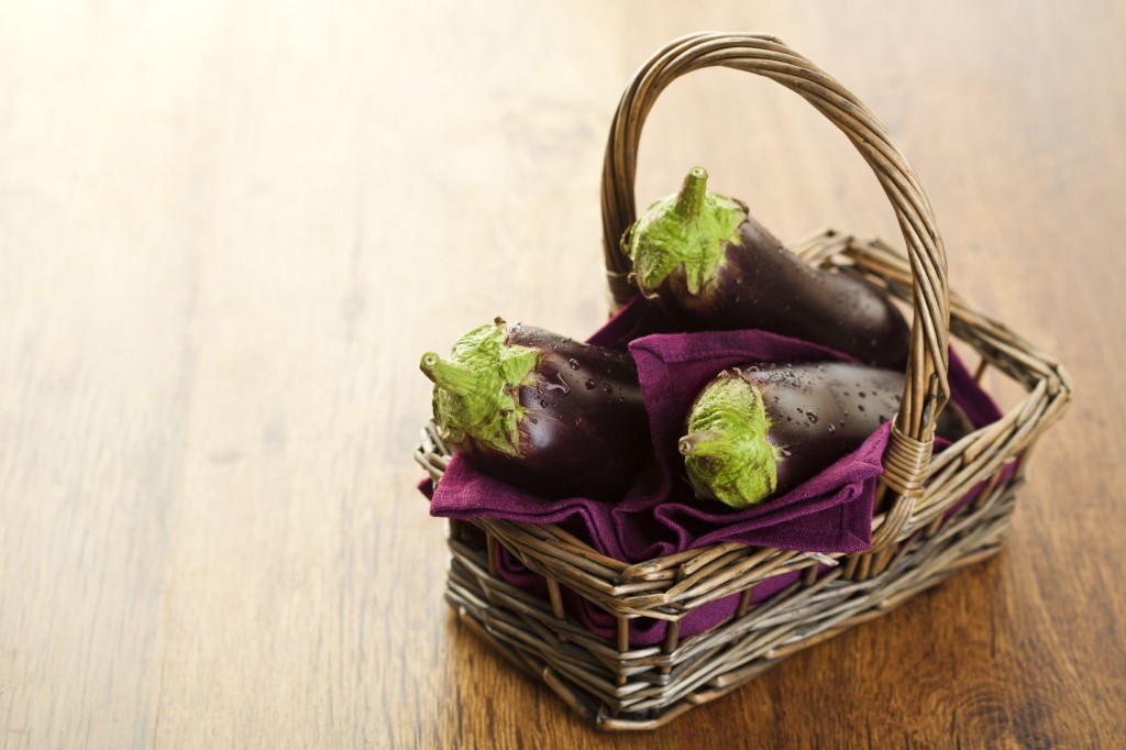 14953903 - raw aubergines or eggplants in basket on wooden backround.