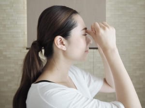 眉間と鼻のつけ根の境目にある溝（さんちく）に親指をあて、上に押し上げるように圧をかけます。このツボは眼精疲労や目の周辺の血行促進などに効果的といわれるツボなので、仕事中などに目が疲れた時にもやってみてください